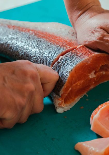 hand-cutting-raw-headless-salmon-fish-laying-on-bl-2022-05-19-15-33-07-utc.jpg